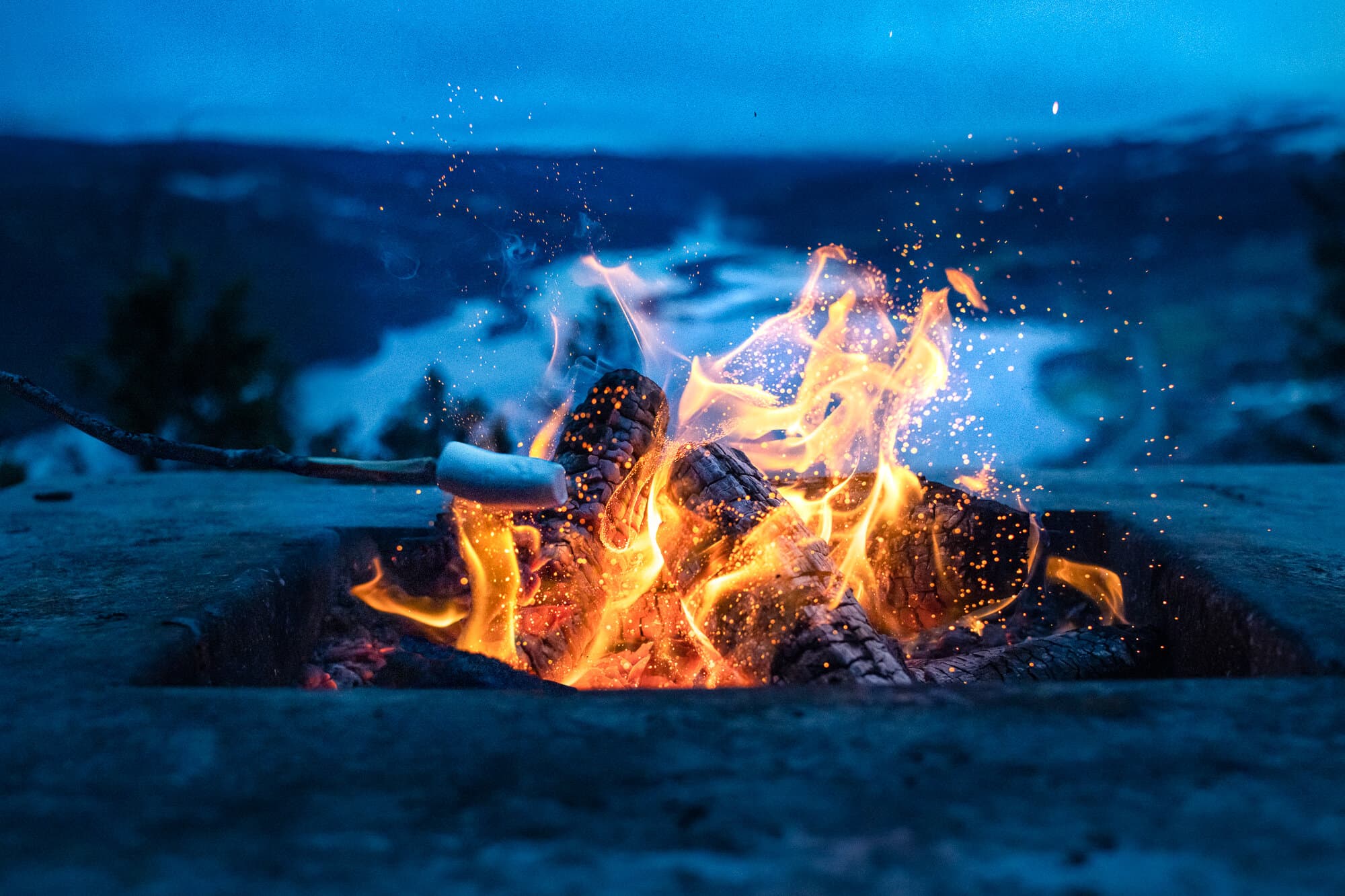 Marshmallow grillas över elden i skymningen